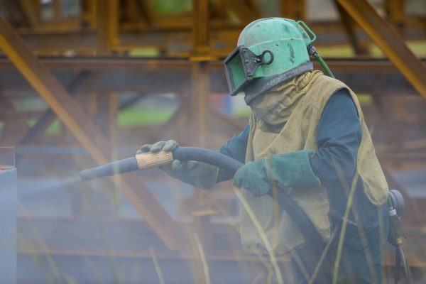 worker showing the protective equipment for safety when sand blasting with a high pressure hose system